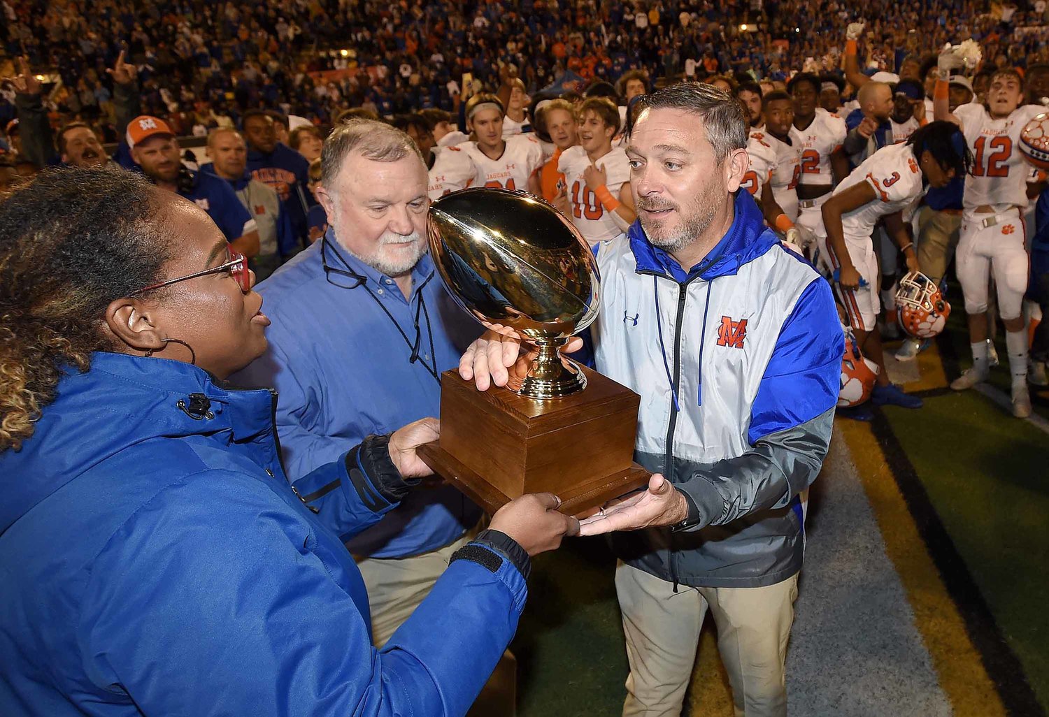 Madison Central head coach Toby Collums receives the trophy after the Jaguars beat Brandon in the MHSAA Class 6A Football State Championship game.